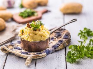 mashed potatoes in old panl decorated parsley herbs and roasted bacon pieces.