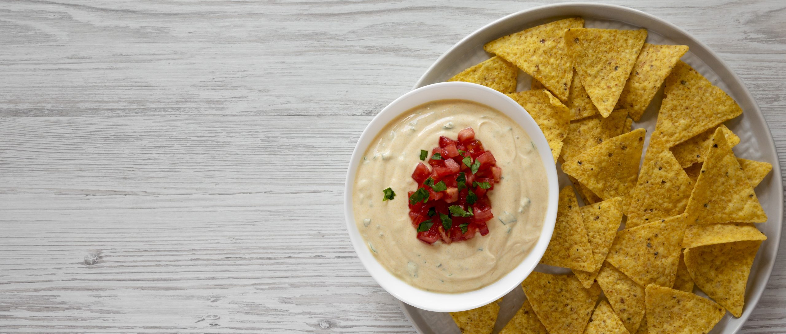 dairy-free cheesy dip in a bowl, yellow tortilla chips, overhead v