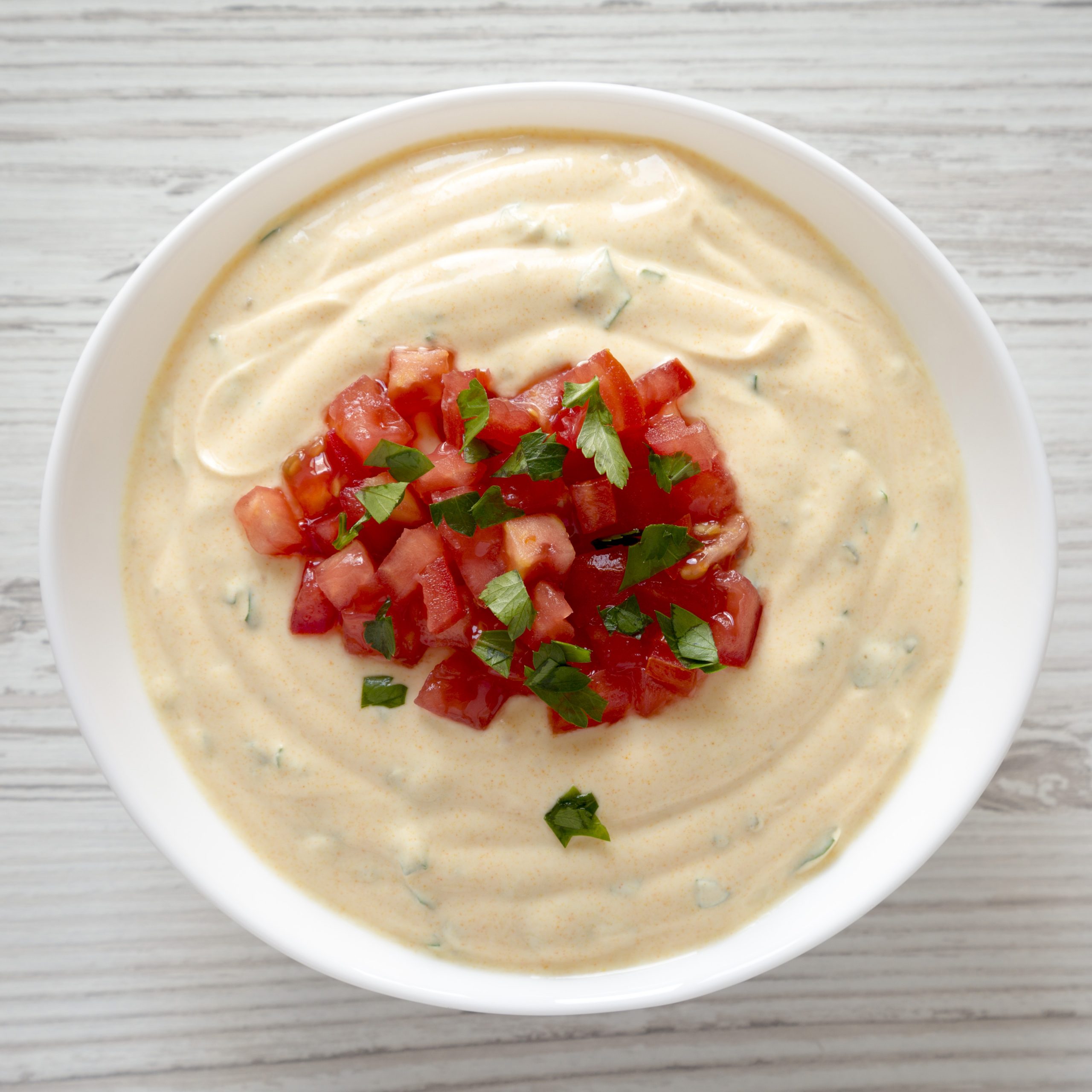 top view, dairy-free cheesy dip in a bowl over white wooden surfac
