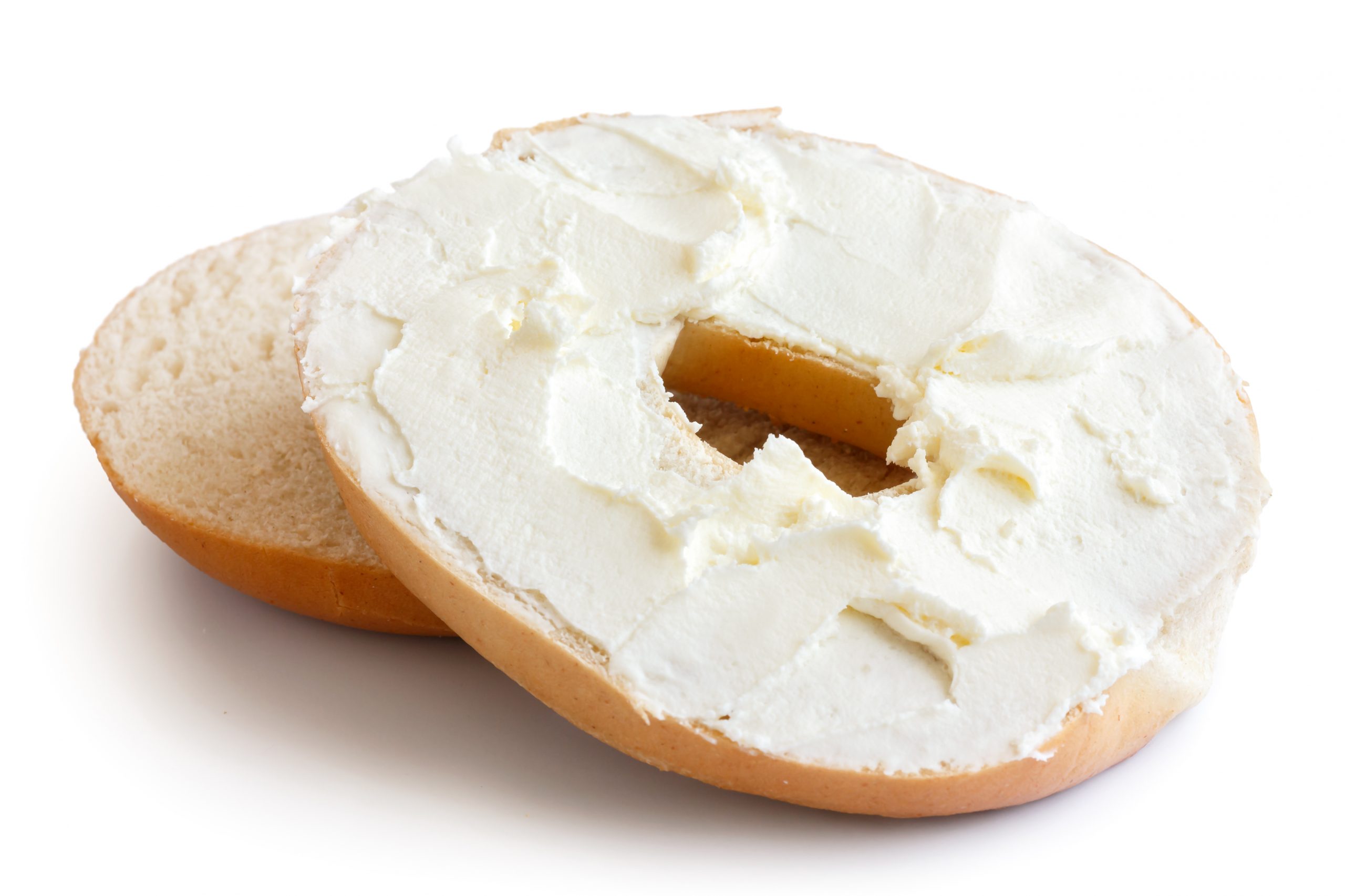 plain bagel cut in half and spread with dairy-free cream cheese. isolated on white.