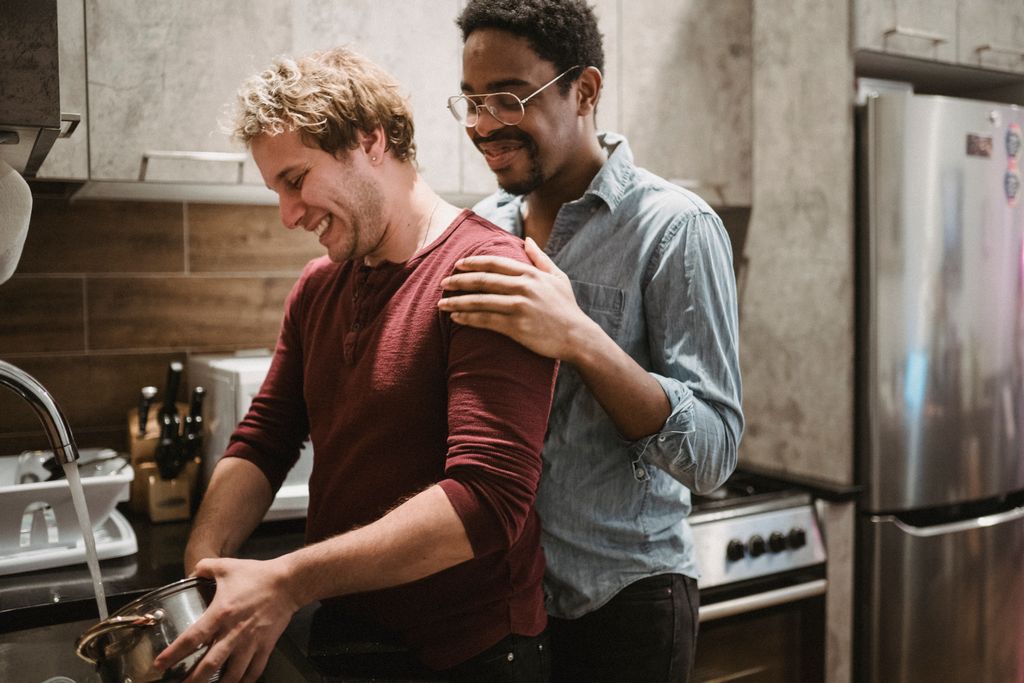 A happy interracial gay couple enjoying quality time together while cooking in a modern kitchen.